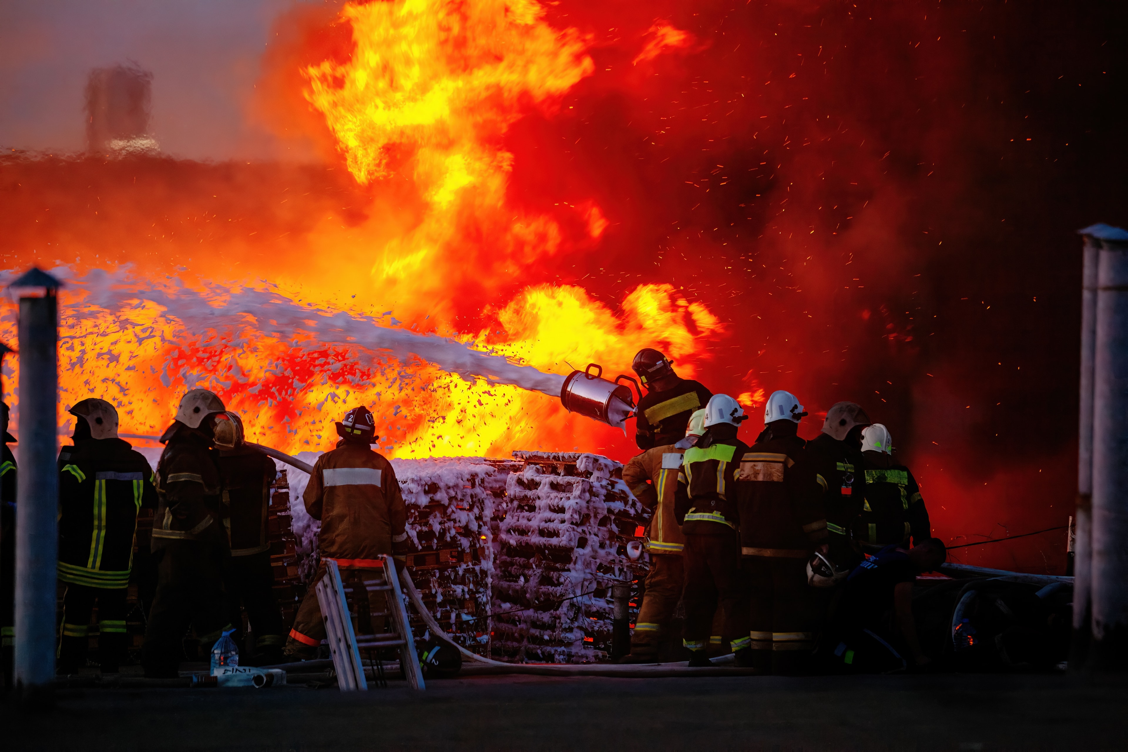 Firefighters battling a large industrial fire using foam